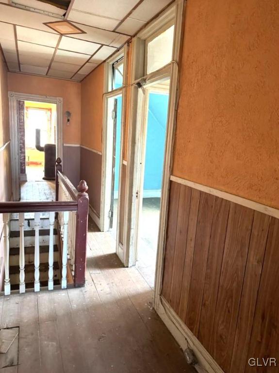 corridor with a paneled ceiling and wooden walls