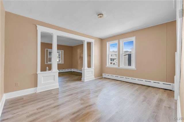 unfurnished room featuring baseboard heating, light hardwood / wood-style flooring, and decorative columns