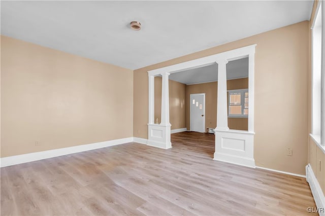 empty room with light wood-type flooring and decorative columns