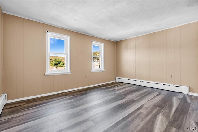 unfurnished room with a textured ceiling, wood walls, dark hardwood / wood-style floors, and a baseboard heating unit