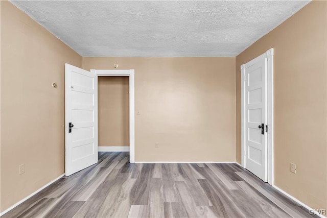 unfurnished room with hardwood / wood-style floors and a textured ceiling