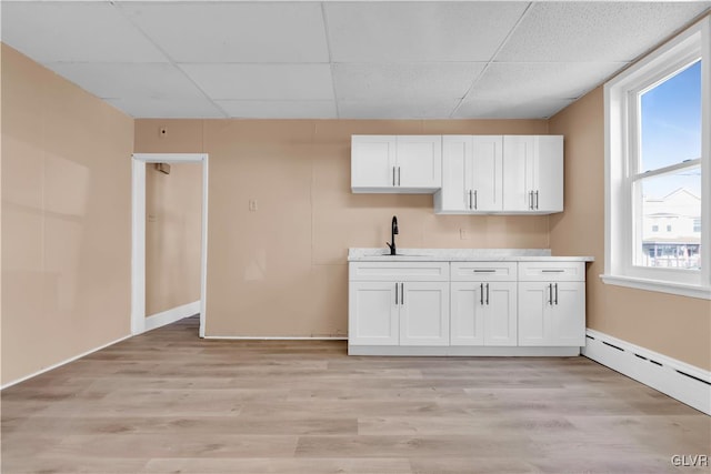 interior space with white cabinetry, sink, a baseboard radiator, and light hardwood / wood-style flooring