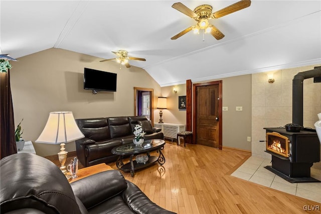 living room with vaulted ceiling, a wood stove, tile walls, ceiling fan, and light hardwood / wood-style flooring