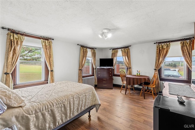 bedroom featuring hardwood / wood-style flooring, a textured ceiling, and radiator