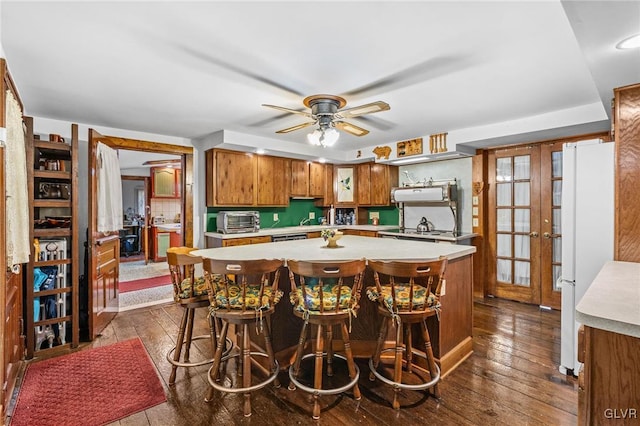 kitchen featuring a kitchen bar, dark hardwood / wood-style flooring, a kitchen island, and white fridge