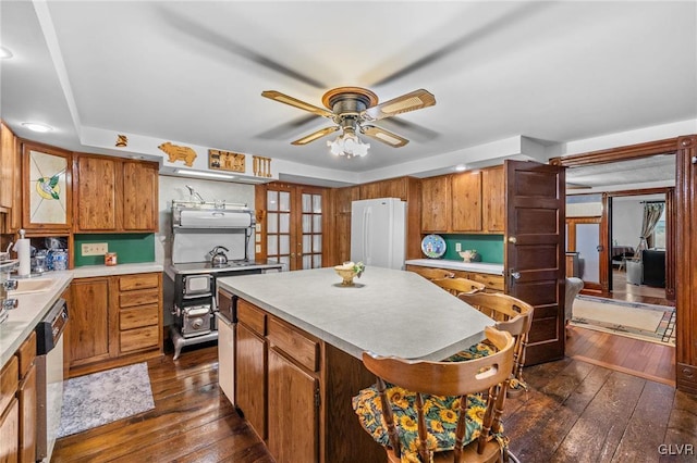 kitchen featuring dark wood-type flooring, a center island, white refrigerator, stainless steel dishwasher, and ceiling fan