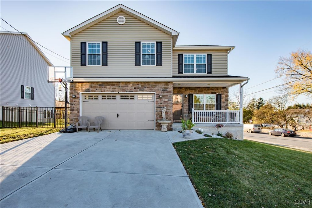 view of property with covered porch, a garage, and a front lawn