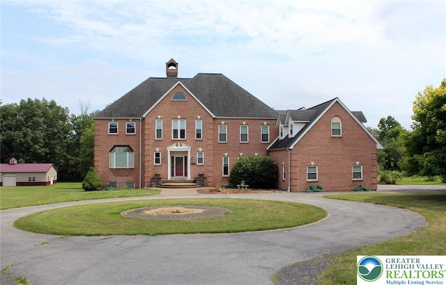 3045 W Scenic Dr, Moore Twp, PA 18038 - colonial home featuring a front yard, curved driveway, brick siding, a chimney, and roof with shingles
