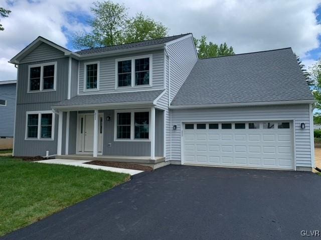 front of property featuring covered porch, a garage, and a front lawn