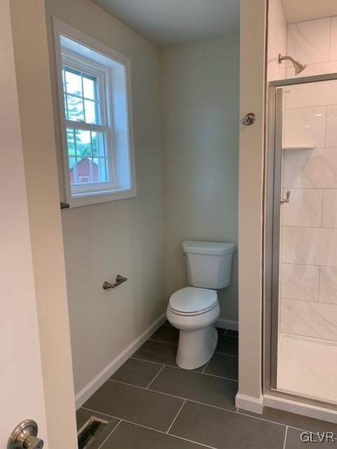 bathroom featuring tile patterned flooring, toilet, and walk in shower