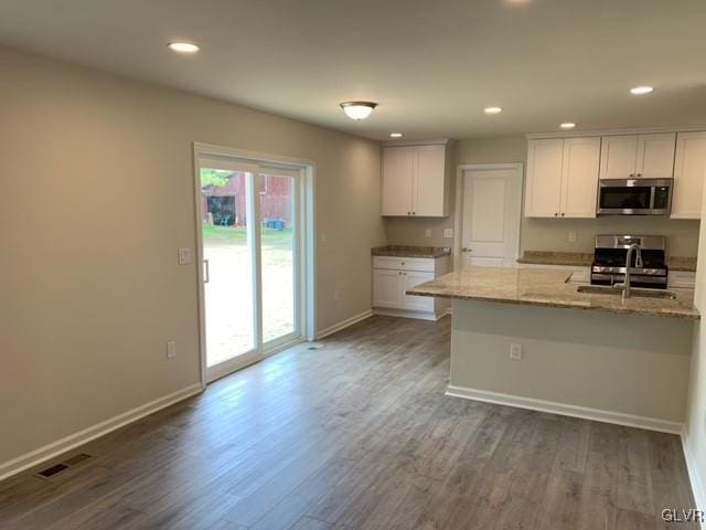 kitchen featuring a breakfast bar, white cabinets, dark hardwood / wood-style floors, appliances with stainless steel finishes, and light stone counters