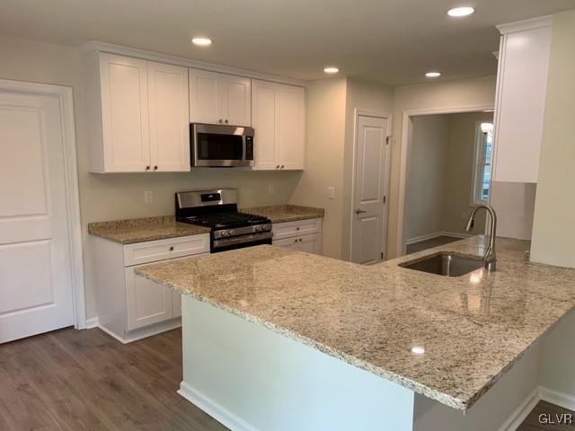 kitchen with white cabinets, kitchen peninsula, sink, and appliances with stainless steel finishes