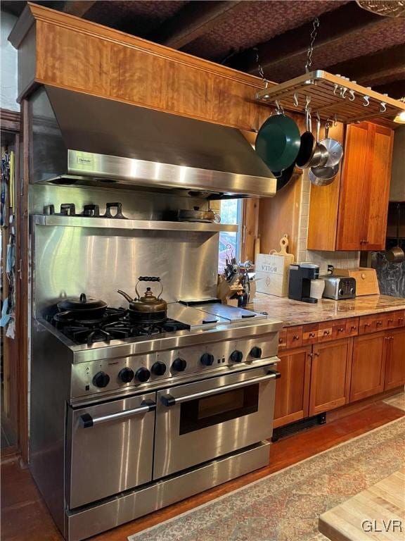 kitchen featuring beamed ceiling, decorative backsplash, range with two ovens, and range hood