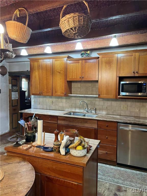 kitchen with backsplash, sink, beamed ceiling, and stainless steel appliances