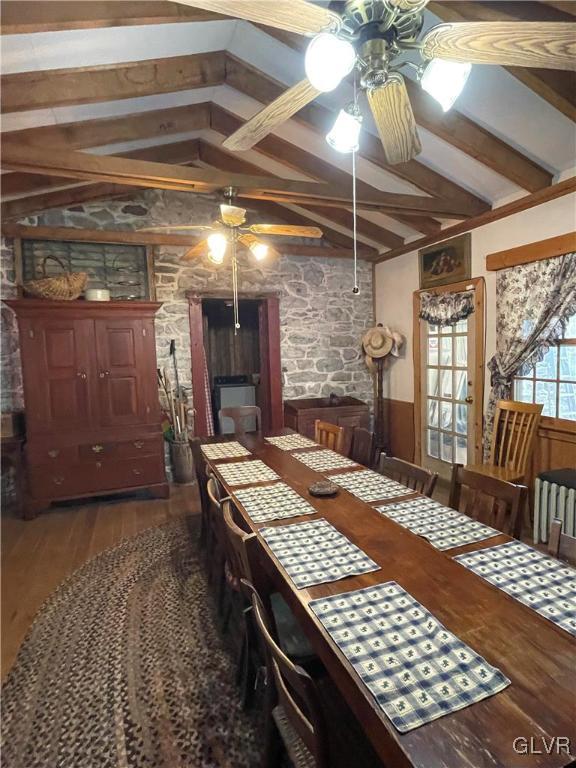 dining space with ceiling fan, lofted ceiling with beams, and dark hardwood / wood-style floors