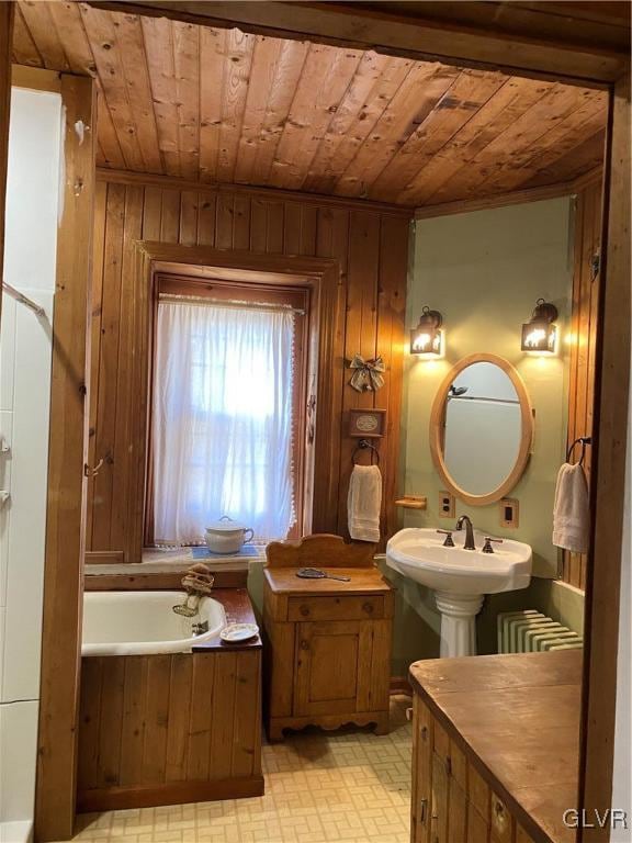 bathroom featuring a bathing tub, wood walls, radiator heating unit, and wooden ceiling