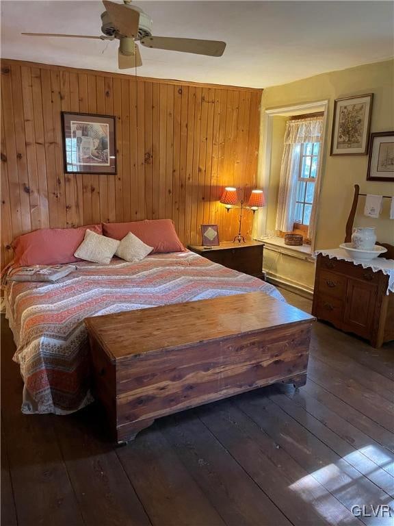 bedroom featuring hardwood / wood-style flooring, ceiling fan, and wooden walls