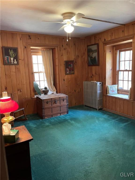 misc room featuring ceiling fan, radiator heating unit, dark carpet, and wood walls