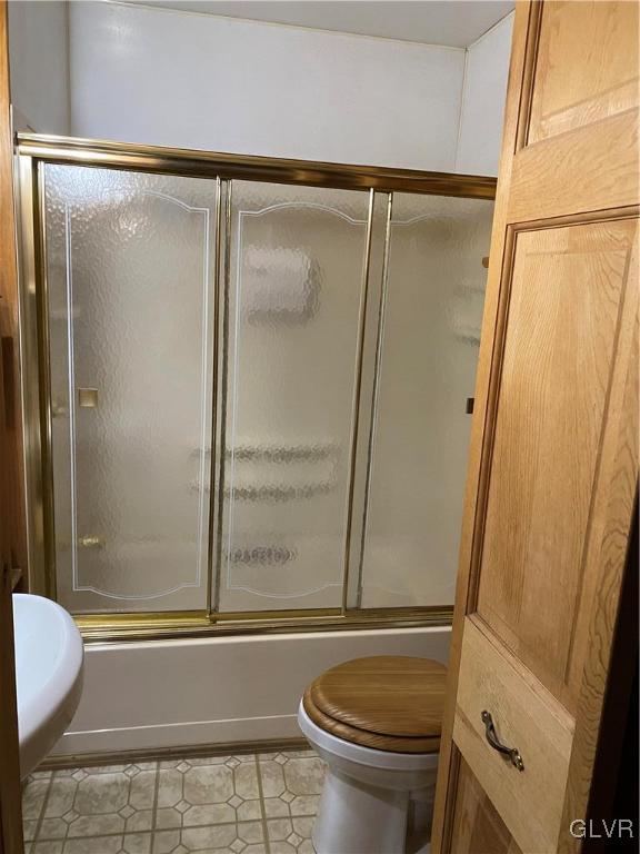 bathroom with tile patterned flooring, toilet, and shower / bath combination with glass door