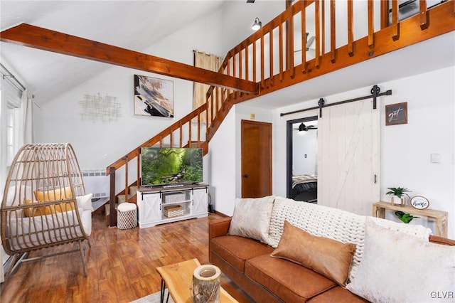 living room featuring beamed ceiling, a barn door, wood-type flooring, and high vaulted ceiling