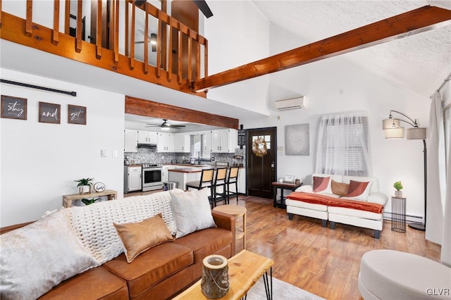 living room featuring light wood-type flooring, a wall unit AC, ceiling fan, high vaulted ceiling, and beamed ceiling