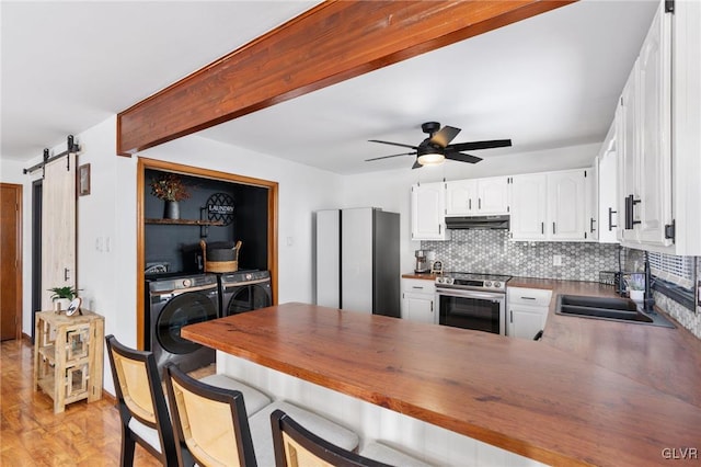 kitchen featuring white cabinets, electric range, a barn door, washing machine and dryer, and kitchen peninsula