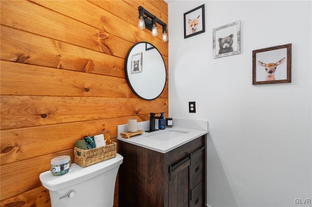 bathroom featuring wooden walls, vanity, and toilet