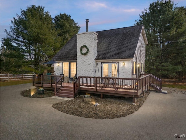 back house at dusk featuring a wooden deck