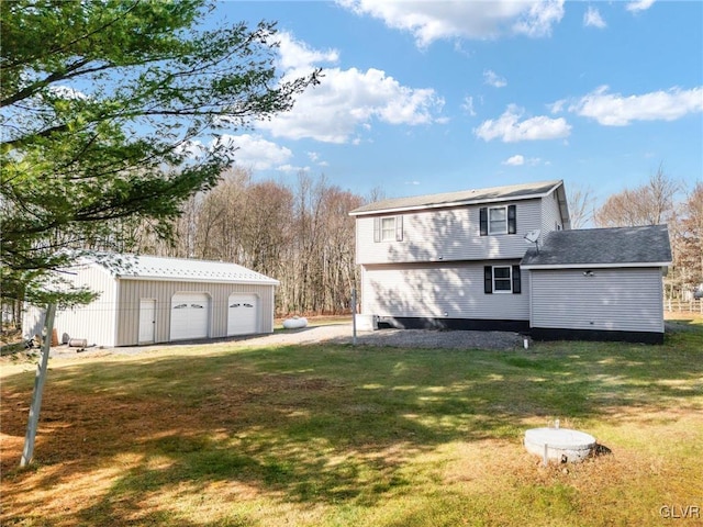 back of house with a lawn, a garage, and an outbuilding