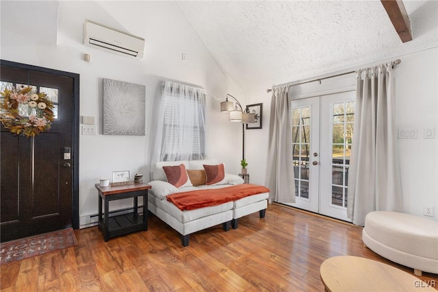 sitting room featuring french doors, a textured ceiling, vaulted ceiling, wood-type flooring, and an AC wall unit