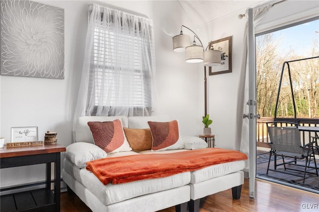 living area with hardwood / wood-style flooring, a healthy amount of sunlight, ornamental molding, and baseboard heating