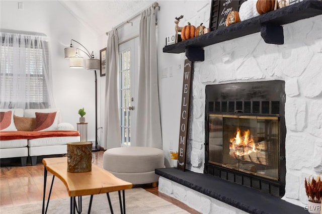 living area with a fireplace, ornamental molding, and light wood-type flooring