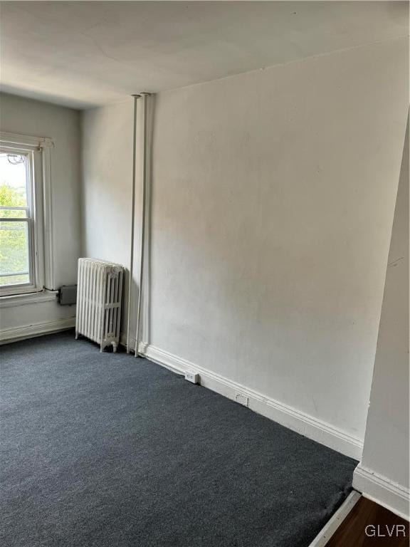 carpeted spare room with radiator heating unit