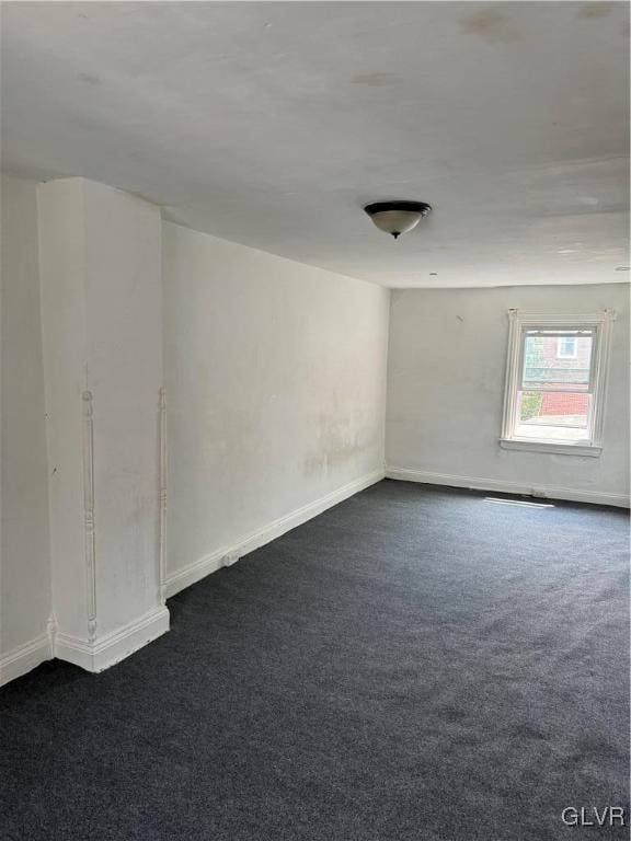 unfurnished room with dark colored carpet