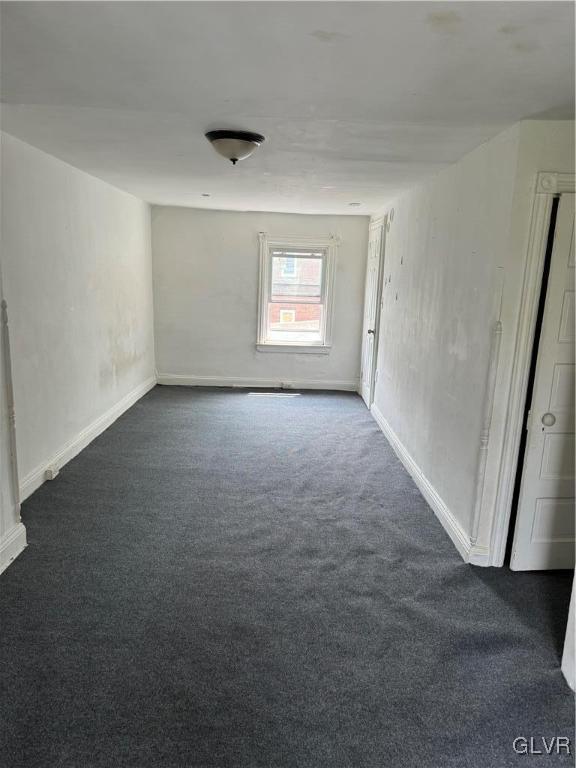 spare room with dark carpet