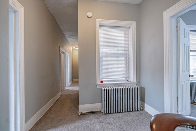 hallway with light colored carpet and radiator heating unit