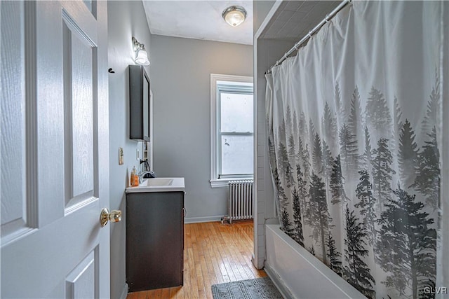 bathroom with hardwood / wood-style floors, vanity, radiator, and shower / tub combo