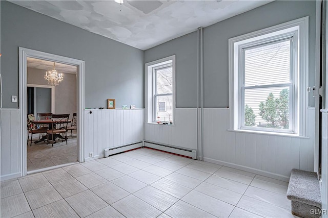 interior space featuring light tile patterned floors, baseboard heating, and an inviting chandelier