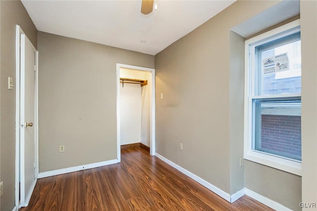 unfurnished bedroom with dark hardwood / wood-style floors, a spacious closet, a closet, and ceiling fan