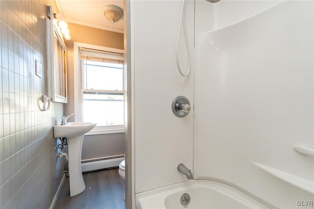 bathroom featuring shower / bathing tub combination, a baseboard radiator, hardwood / wood-style flooring, tile walls, and toilet