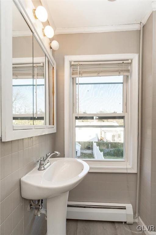 bathroom featuring ornamental molding, tile walls, a wealth of natural light, and a baseboard heating unit