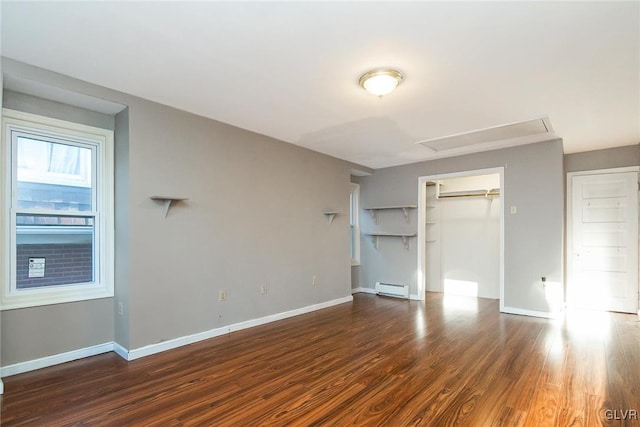 unfurnished bedroom with baseboard heating, a closet, and dark wood-type flooring