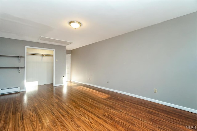 unfurnished bedroom with baseboard heating, a closet, and dark wood-type flooring