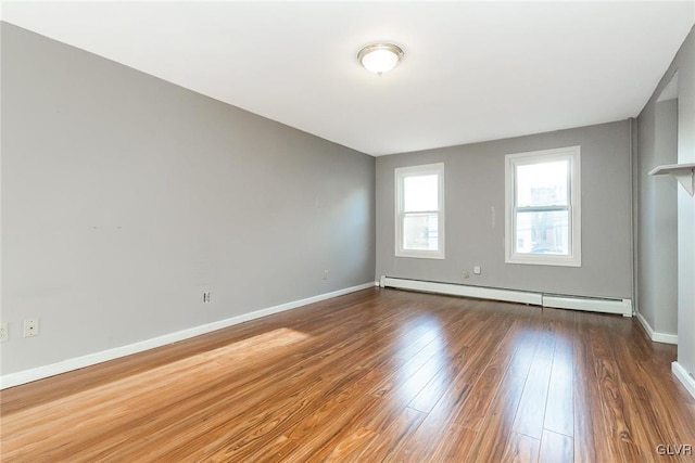 empty room featuring dark hardwood / wood-style flooring and a baseboard heating unit