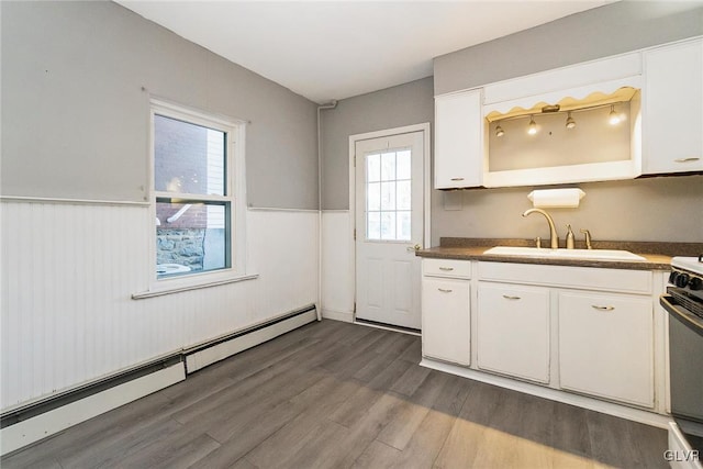 kitchen with sink, dark wood-type flooring, a baseboard radiator, range with electric stovetop, and white cabinets