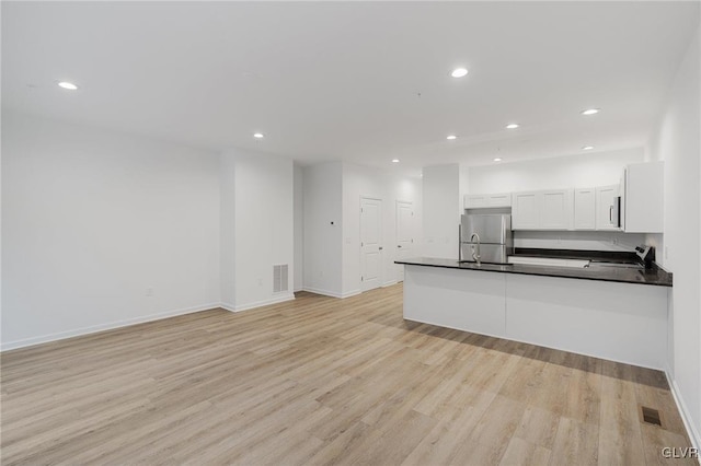 kitchen featuring light wood-style flooring, stainless steel appliances, visible vents, white cabinetry, and dark countertops