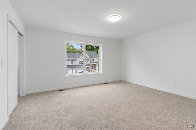 unfurnished bedroom featuring light colored carpet and a closet