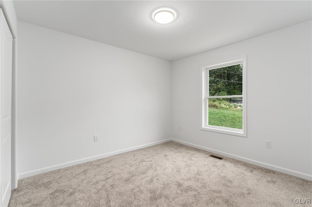 spare room featuring carpet floors, visible vents, and baseboards