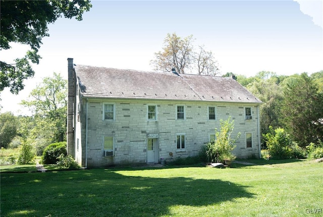 back of house with cooling unit and a lawn