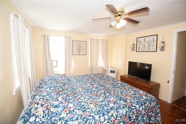 bedroom featuring multiple windows, ceiling fan, crown molding, and radiator